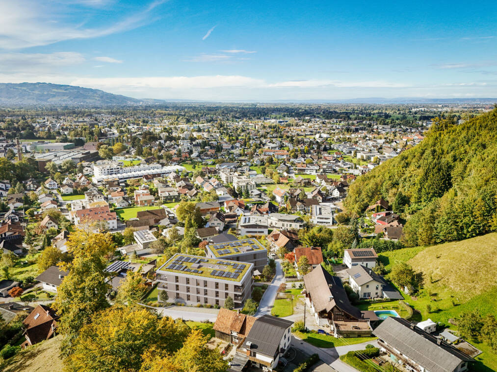 Die Ansicht aus südöstlicher Richtung veranschaulicht die beiden geplanten Wohngebäude in ihrer Hanglage und ihre Einbettung in das bestehende Wohnumfeld von Dornbirn. Luftbildvisualisierung aus Südosten Fallenberggasse