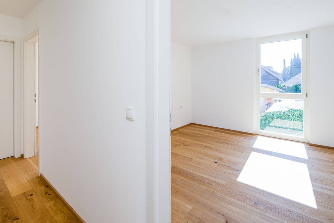 Der helle Innenraum der Top 3 verbindet Echtholzparkett mit klaren Wandflächen und großzügigen Fensteröffnungen. Die sichtbare Raumaufteilung bietet eine sachliche Grundlage für die individuelle Möblierung. Wohnraum der Eigentumswohnung Top 3