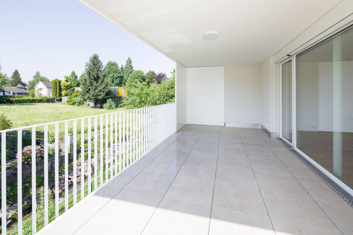Die weitläufige, geschützte Terrasse erweitert den Wohnraum der Top 3 ins Freie. Der offene Blick auf die umgebende Begrünung unterstreicht die ruhige Lage am Inselbach. Terrasse der Eigentumswohnung Top 3